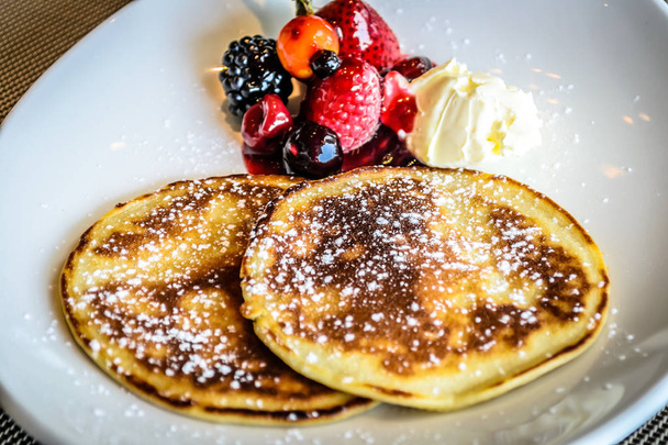 pancake with icing sugar with strawberry and blueberrry compote and fresh cream - Foto, imagen