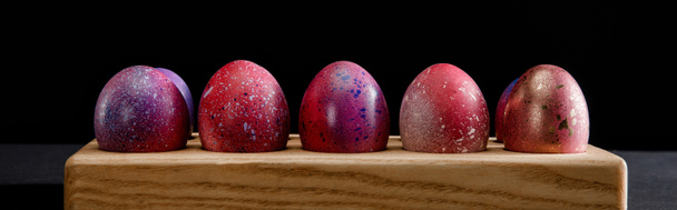 Colorful Easter eggs on wooden board on black background, panoramic shot - Fotó, kép