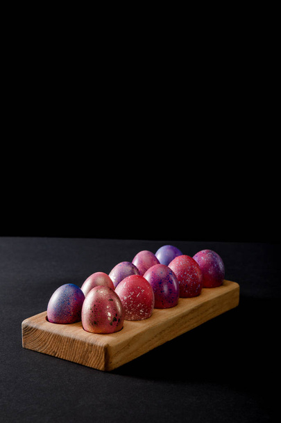 Colorful Easter eggs on wooden board on grey and black background - Fotó, kép