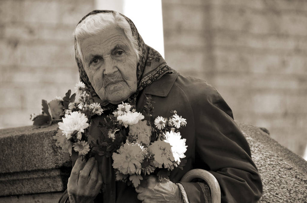 een portret van een oudere vrouw met een boeket bloemen - Foto, afbeelding