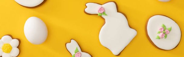 Top view of tasty easter cookies and chicken egg on yellow background, panoramic shot - Foto, imagen