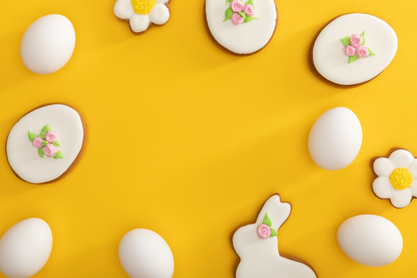 Top view of tasty easter cookies and chicken eggs on yellow  - Photo, image