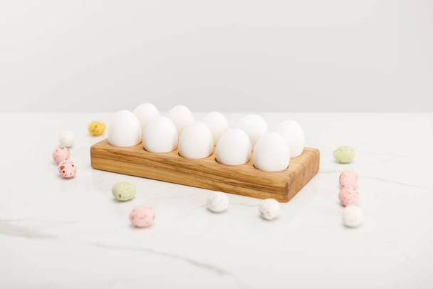 Huevos coloridos de codorniz y pollo sobre tabla de madera sobre fondo gris
 - Foto, imagen
