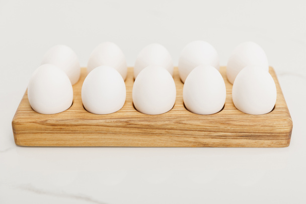 Drewniana taca na jajka z kurzymi jajami na białym tle - Zdjęcie, obraz