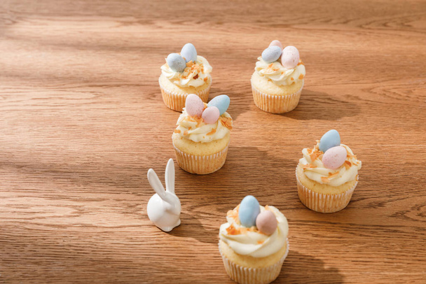 Délicieux cupcakes avec lapin décoratif sur fond en bois
 - Photo, image
