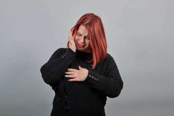 girl in black sweater an unhappy woman in despair touches her hands to face - Fotografie, Obrázek