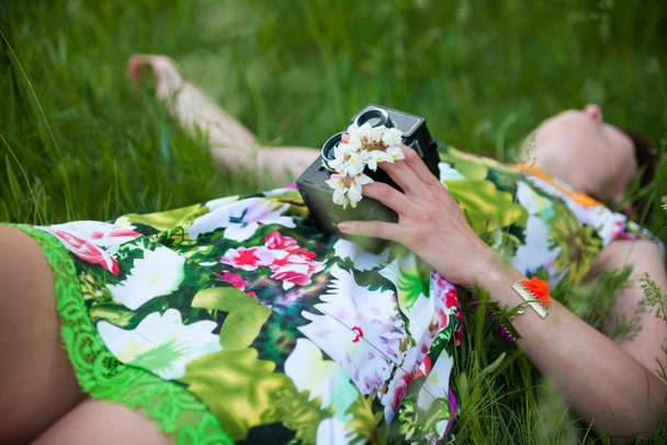 Sexy woman with vintage camera lying in the grass. - Foto, afbeelding