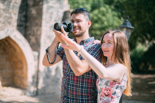 Los amantes toman fotos de las atracciones cerca de la pared de piedra del templo. Un par de recién casados admiran la antigua iglesia. Luna de miel en viaje
 - Foto, Imagen