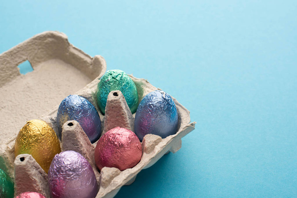 Шоколадные пасхальные яйца в лотке для яиц на голубом фоне
 - Фото, изображение