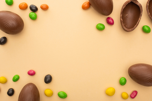 Top view of chocolate eggs and tasty sweets on beige background - Φωτογραφία, εικόνα