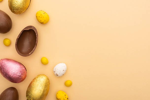 Top view of delicious chocolate and quail eggs with sweets on beige background - Photo, Image