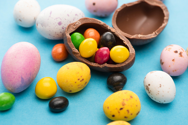 Close up of Easter chicken, quail and chocolate eggs with candies on blue background - Fotoğraf, Görsel