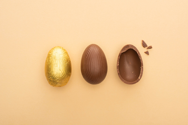 Bovenaanzicht van chocolade paaseieren op beige achtergrond - Foto, afbeelding