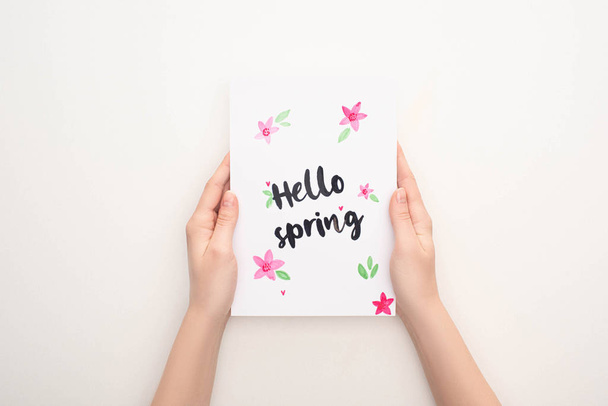 Vue recadrée de la femme tenant la carte avec lettrage bonjour printemps sur fond blanc
 - Photo, image