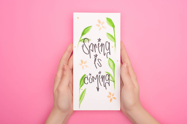 Partial view of woman holding card with spring is coming lettering on pink - Photo, Image