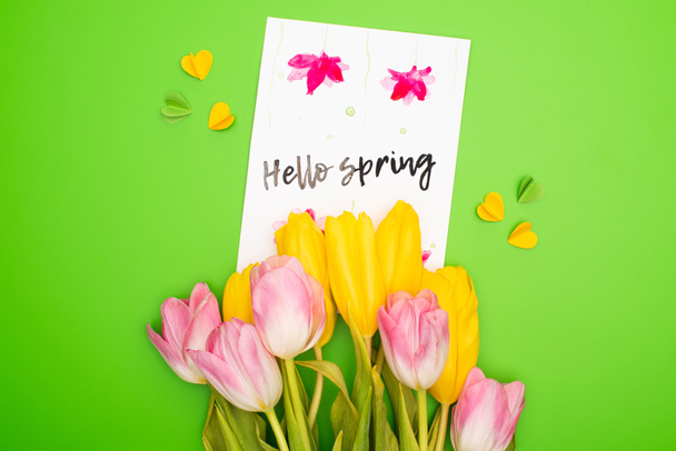 Horní pohled na kytici, pohlednici s nápisem Hello Spring a ozdobnými srdíčky na růžové - Fotografie, Obrázek