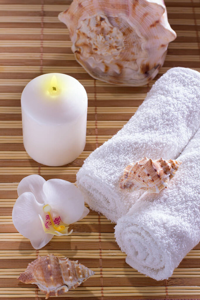 Lázeňské prostředí s ručníkem, mušlemi, aromatickým olejem, orchidejí a svíčkou. Relax koncept.  - Fotografie, Obrázek