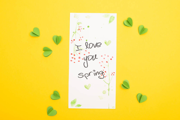 Vista superior de la tarjeta con I love you letras de primavera y corazones verdes decorativos sobre fondo amarillo
 - Foto, Imagen