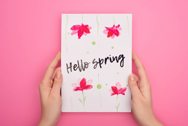 Vue recadrée de la femme tenant la carte avec lettrage bonjour printemps sur fond rose
 - Photo, image