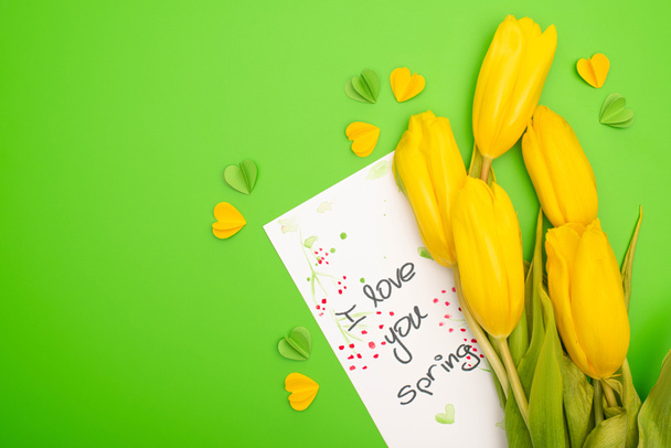 Top view of yellow tulips, card with I love you spring lettering and decorative hearts on green background - Photo, Image