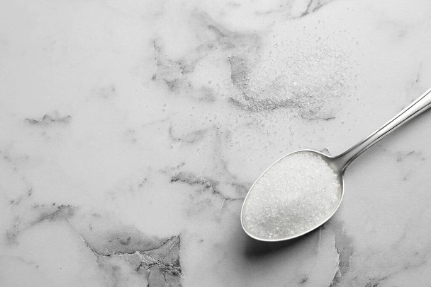 Spoon of white sugar on marble table, top view. Space for text - Foto, afbeelding