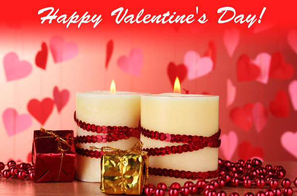 Beautiful candles with romantic decor on a wooden table on a red background - Fotoğraf, Görsel