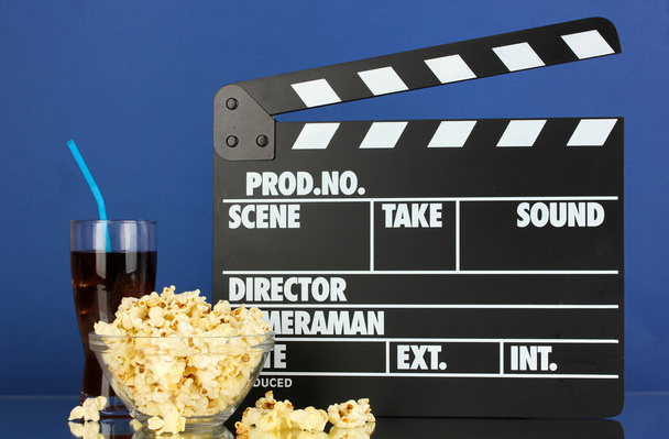 Movie clapperboard, cola and popcorn on blue background - Фото, изображение