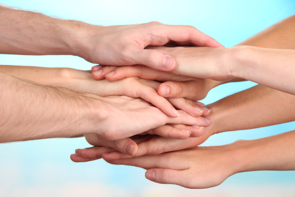 United hands on bright background. Conceptual photo of teamwork - Foto, afbeelding