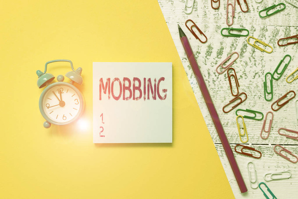 Word writing text Mobbing. Business concept for Bulling of individual specially at work Emotional abuse Stress Notepad marker pen colored paper sheet clips alarm clock wooden background. - Photo, Image