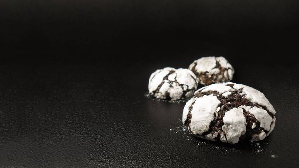 Homemade chocolate cookies. Chocolate brownie cookies in powdered sugar in black background. Selective focus - Foto, Imagem