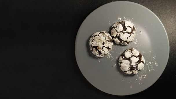 Homemade chocolate cookies. Chocolate brownie cookies in powdered sugar in black background. Selective focus - Photo, Image