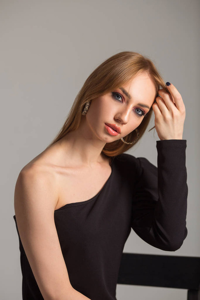 beautiful young woman with make-up in a black dress on a gray background - Foto, afbeelding