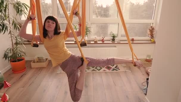Fly Yoga. Woman doing yoga exercises on a hammock in an apartment. - Video