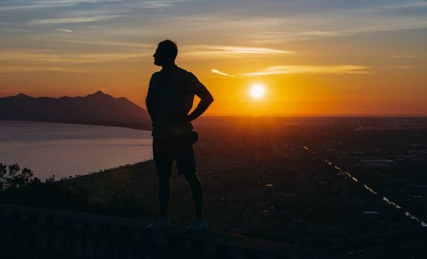 Voyage. Un gars se tient au sommet d'une montagne et regarde le coucher du soleil
. - Photo, image