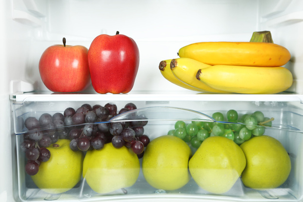 Milk bottles, vegetables and fruits in open refrigerator. Weight loss diet concept. - Photo, image