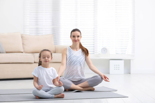 Young mother with little daughter practicing yoga at home - Valokuva, kuva