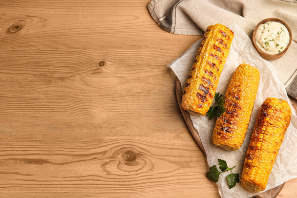 Delicious grilled corn cobs on wooden table, flat lay. Space for text - Foto, Imagem