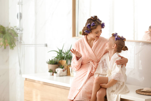 Happy mother and daughter with curlers in bathroom - Fotografie, Obrázek