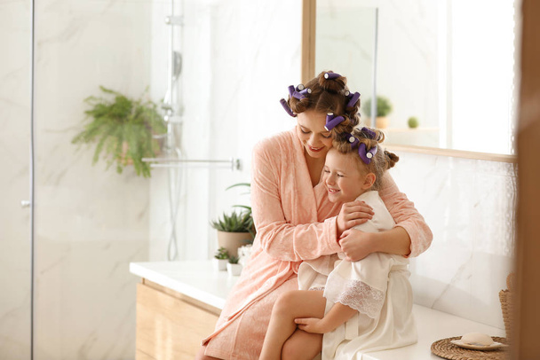 Happy mother and daughter with curlers in bathroom - Foto, afbeelding