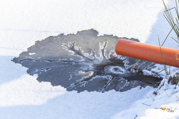 le liquide coule du tuyau dans le lac et fait fondre la glace. Il y a une teinte. Gros plan
. - Photo, image