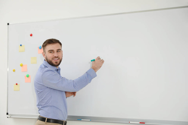 Young teacher writing on whiteboard in classroom. Space for text - Foto, Imagem