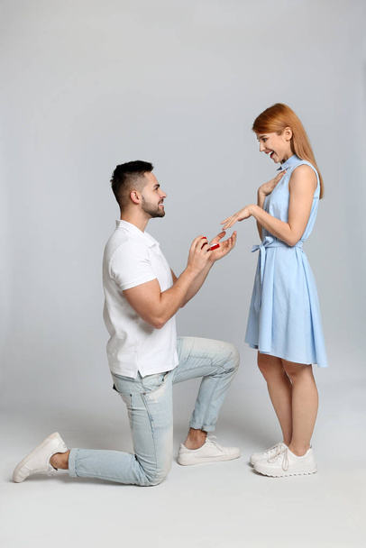 Man with engagement ring making marriage proposal to girlfriend on light grey background - Foto, Bild