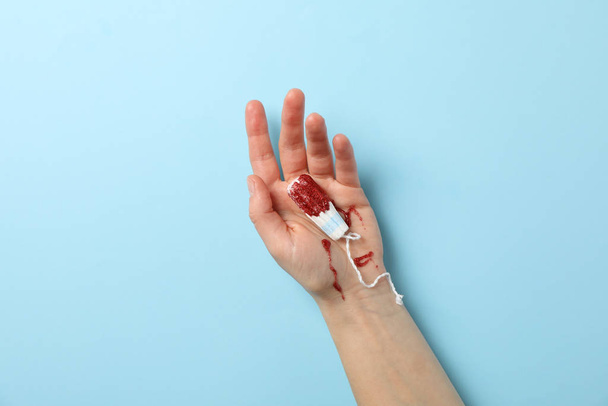 Female hand holding used tampon on blue background, space for text - Fotoğraf, Görsel