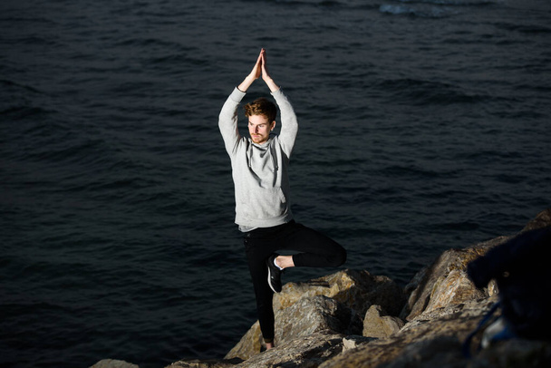 Joven pelirroja practicando yoga, postura del árbol de Vriksasana, para concentrarse y ayudarlo con su mindfullness - Foto, Imagen