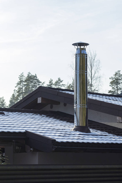 on open air. Stainless steel chimney on a dark roof. Not a lot of snow. Close-up. - Photo, Image