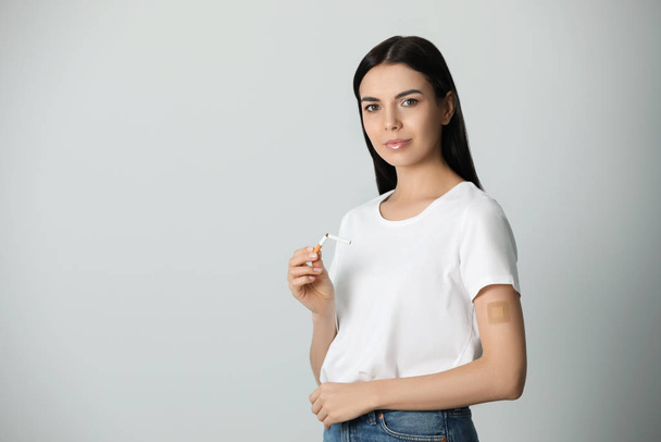 Young woman with nicotine patch and cigarette on light grey background. Space for text - Foto, Imagem