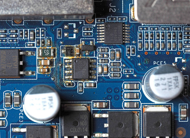 Вид сверху голубой электронной платы с окисленными контактами, конденсаторами и резисторами
 - Фото, изображение