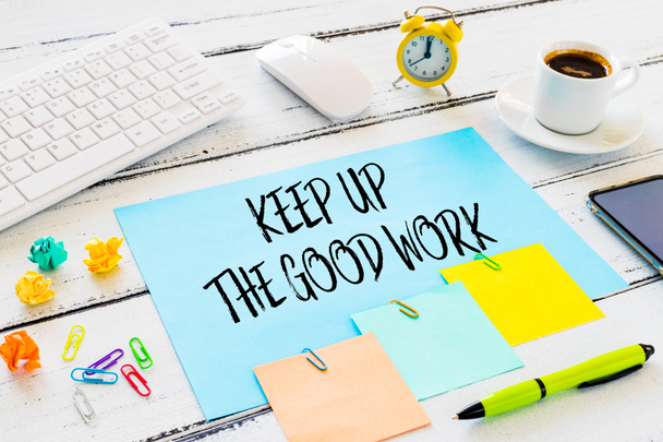 Kancelářská pozice. počítačová klávesnice, káva, budík, zmačkané kuličky papíru, barevné sponky, telefon a karta s mobilizujícím sloganem "Keep Up The Good Work" Koncept efektivní práce - Fotografie, Obrázek