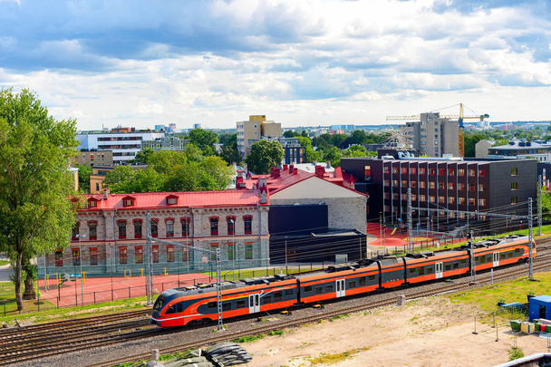 Aerial cityscape of industrial Tallinn area, speed train on railroad, modern urban architecture under overcast sky with heavy clouds, Estonia - Φωτογραφία, εικόνα