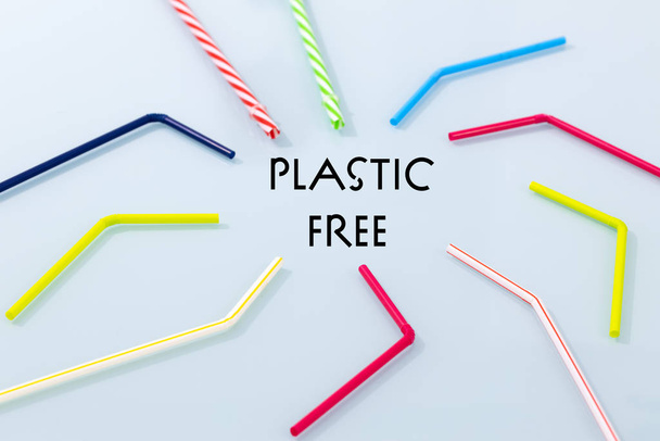 Πολύχρωμα πλαστικά καλαμάκια σε μπλε φόντο και η επιγραφή "Plastik free" Η έννοια του τρόπου ζωής με βάση τη συνειδητή μη χρήση πλαστικών για τη φροντίδα του περιβάλλοντος - Φωτογραφία, εικόνα